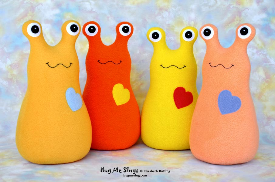 Hug Me Slugs, 12-inch stuffed plushie toys by Elizabeth Ruffing, mango gold, orange, lemon yellow, and orange sherbet fleece