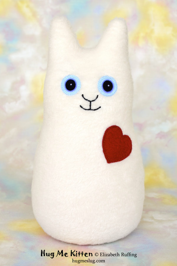 Hug Me Kitten plush art toy, vanilla cream with a red heart, by Elizabeth Ruffing