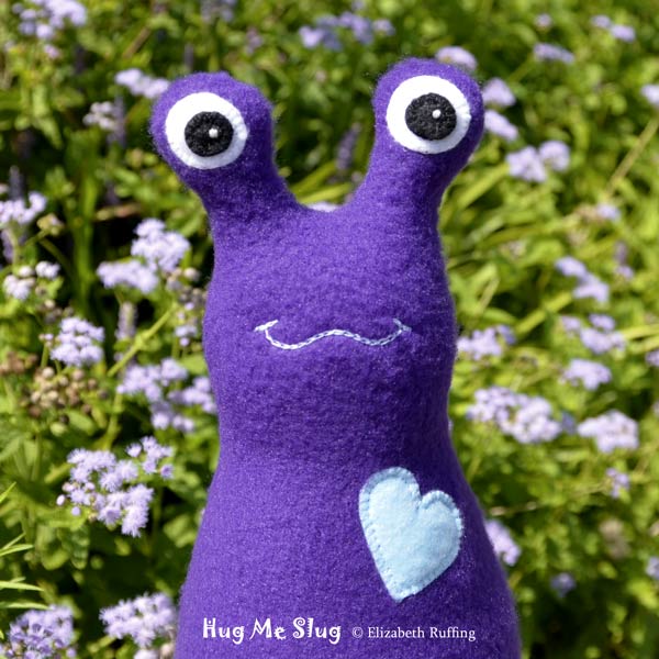 Dark purple fleece Hug Me Slug by Elizabeth Ruffing, with purple ageratum