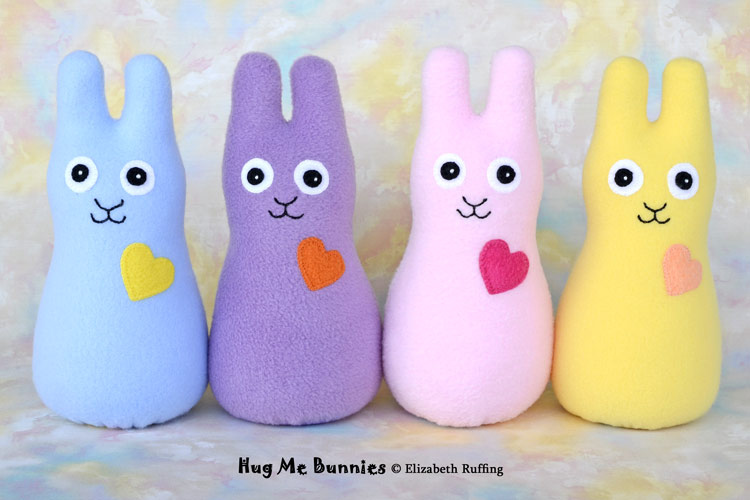 Assorted colors of fleece Hug Me Bunnies by Elizabeth Ruffing, in light blue, lavender, light pink, and daffodil yellow