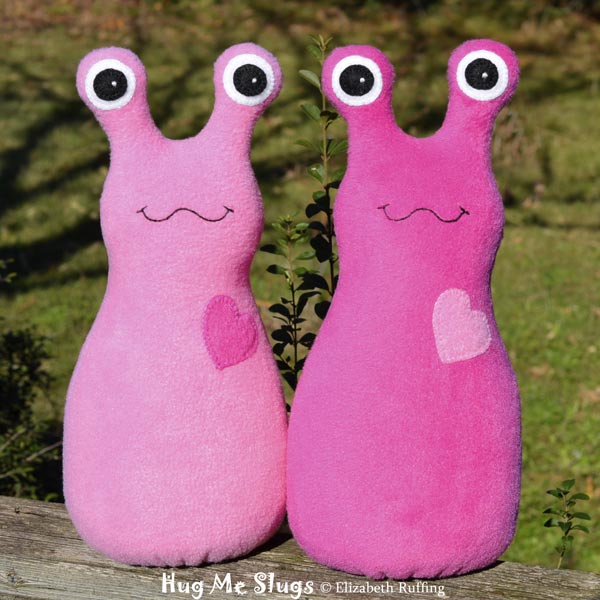 Dark pink and medium pink fleece Hug Me Slug art toys by Elizabeth Ruffing