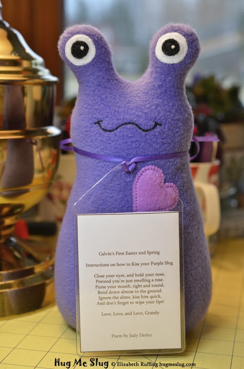 Purple fleece Hug Me Slug handmade stuffed animal art toy by artist Elizabeth Ruffing with a personalized hang tag with a poem on the back