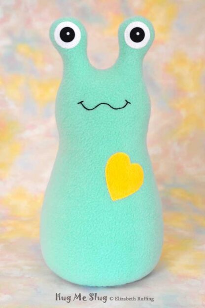 A smiling aqua fleece stuffed animal slug with a yellow heart