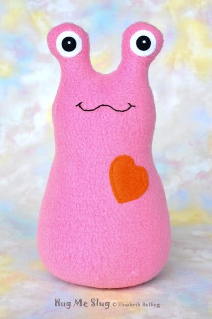 Handmade fleece Hug Me Slug plush toy, medium pink, orange heart by artist Elizabeth Ruffing