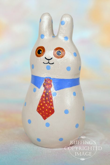 A tan bunny figurine with blue polka dots, a blue collar, and a red tie with yellow polka dots.