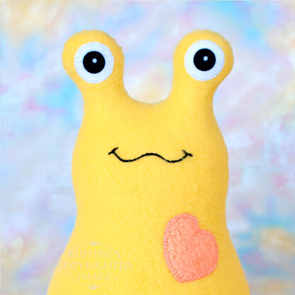 A smiling yellow stuffed animal slug with a soft orange heart