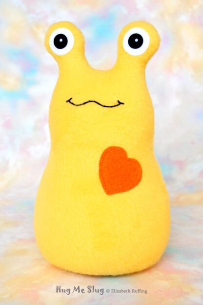 A smiling yellow stuffed animal slug with an orange heart
