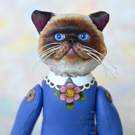 Himalayan cat art doll in blue with a painted white lace color and pink flower at her neck