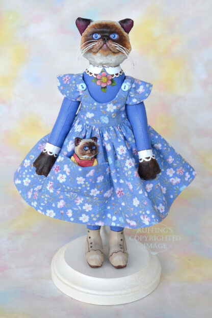 Himalayan cat art doll in a blue floral pinafore with a Himalayan kitten figurine in her pocket