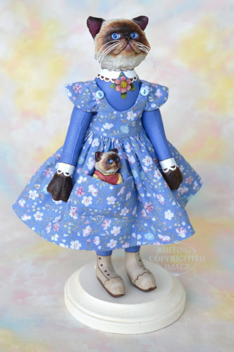 Himalayan cat art doll in a blue floral pinafore with a Himalayan kitten figurine in her pocket