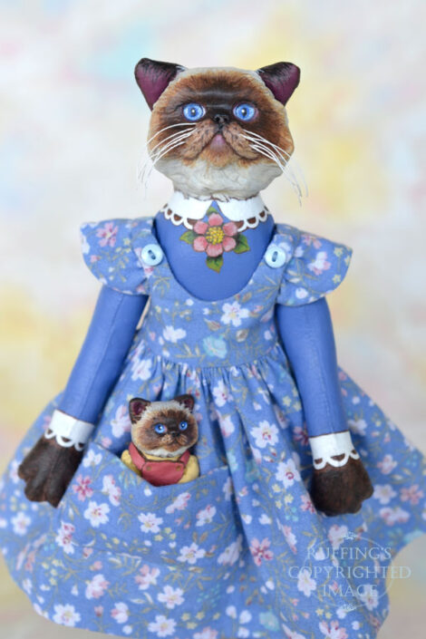 Himalayan cat art doll in a blue floral pinafore with a Himalayan kitten figurine in her pocket
