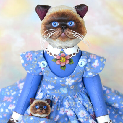 Himalayan cat art doll in a blue floral pinafore with a Himalayan kitten figurine in her pocket