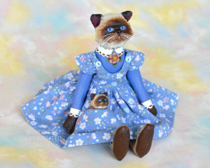 Himalayan cat art doll in a blue floral pinafore with a Himalayan kitten figurine in her pocket