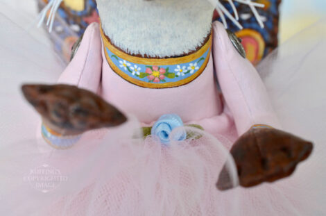 Delicate flowers on the front of a lavender-pink ballet outfit worn by a Siamese cat art doll.