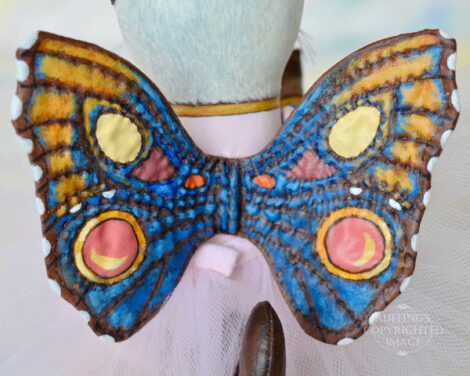 Multicolored wings on a A Siamese cat art doll .