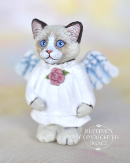 A bi-color ragdoll kitten with angel wings and a rose at her neckline.