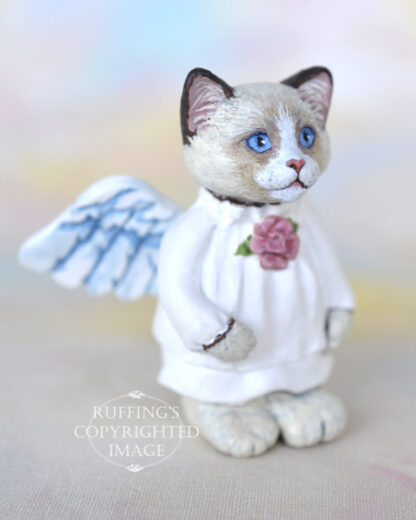 A bi-color ragdoll kitten with angel wings and a rose at her neckline.