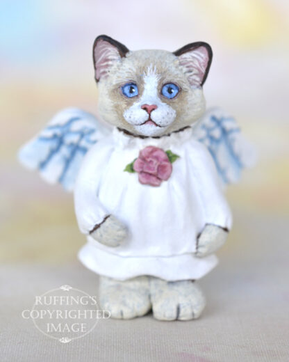 A bi-color ragdoll kitten with angel wings and a rose at her neckline.