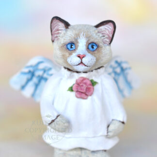 A bi-color ragdoll kitten with angel wings and a rose at her neckline.