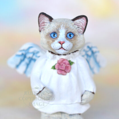 A bi-color ragdoll kitten with angel wings and a rose at her neckline.