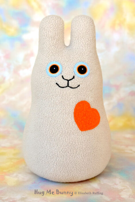 Smiling oatmeal fleece bunny with an orange heart