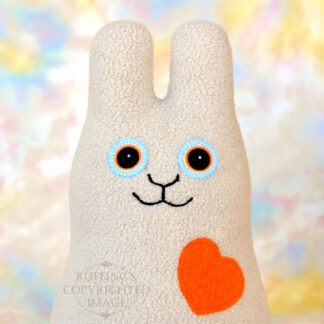 Smiling oatmeal fleece bunny with an orange heart