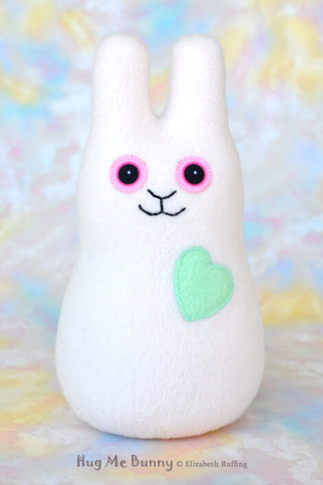 Smiling vanilla colored fleece bunny with a mint green heart
