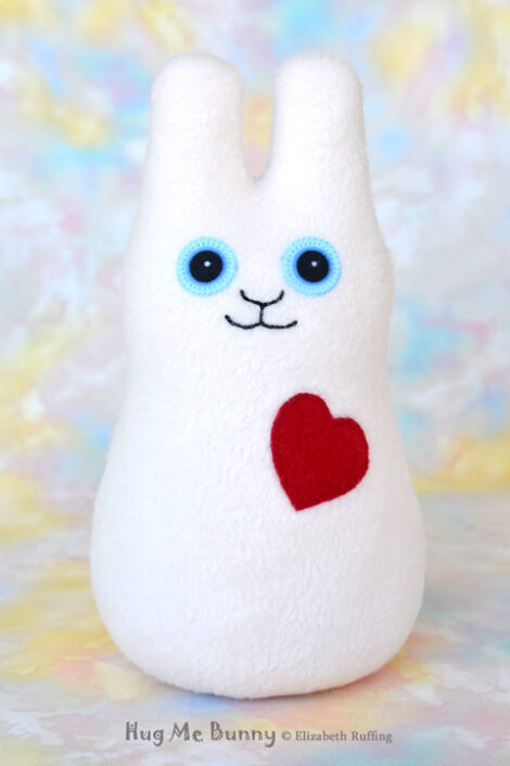 A smiling vanilla colored fleece bunny with a red heart