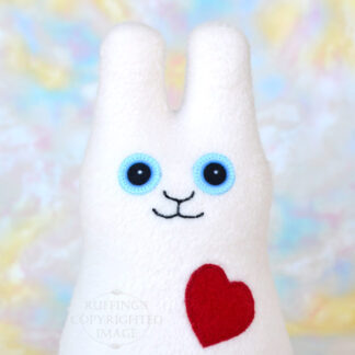 A smiling vanilla colored fleece bunny with a red heart
