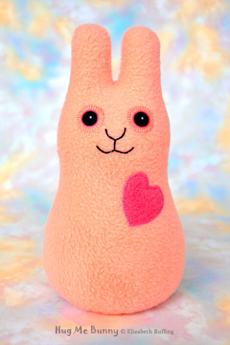 Smiling soft light orange fleece bunny with a coral heart