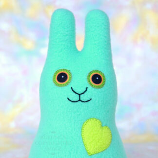 A smiling light aqua green fleece bunny with an apple green heart.