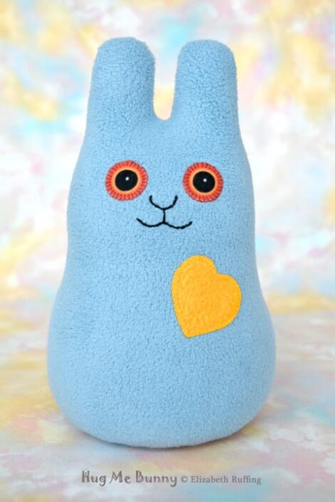 Smiling light gray-blue fleece bunny with a daffodil yellow heart