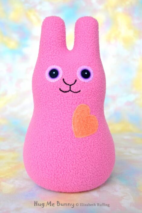 Smiling mauve pink bunny with a coral orange heart