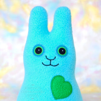 A smiling light turquoise fleece bunny with a Kelly green heart.