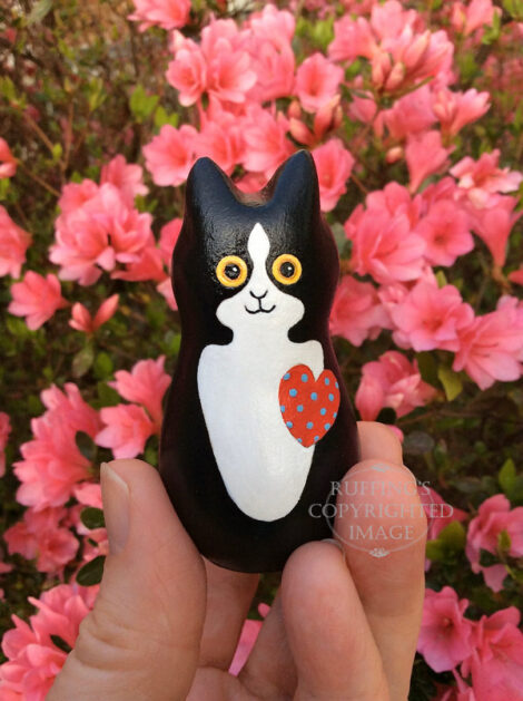 Black-and-white-tuxedo kitten with a red heart with blue polka dots with pink azaleas