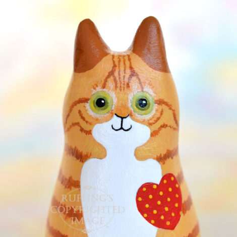 Ginger-and white-tabby cat figurine front view with a red heart with yellow polka dots