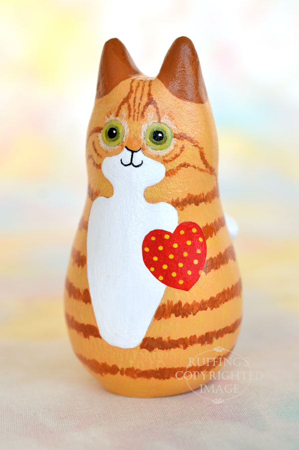 Ginger-and white-tabby cat figurine 3/4 view with a red heart with yellow polka dots